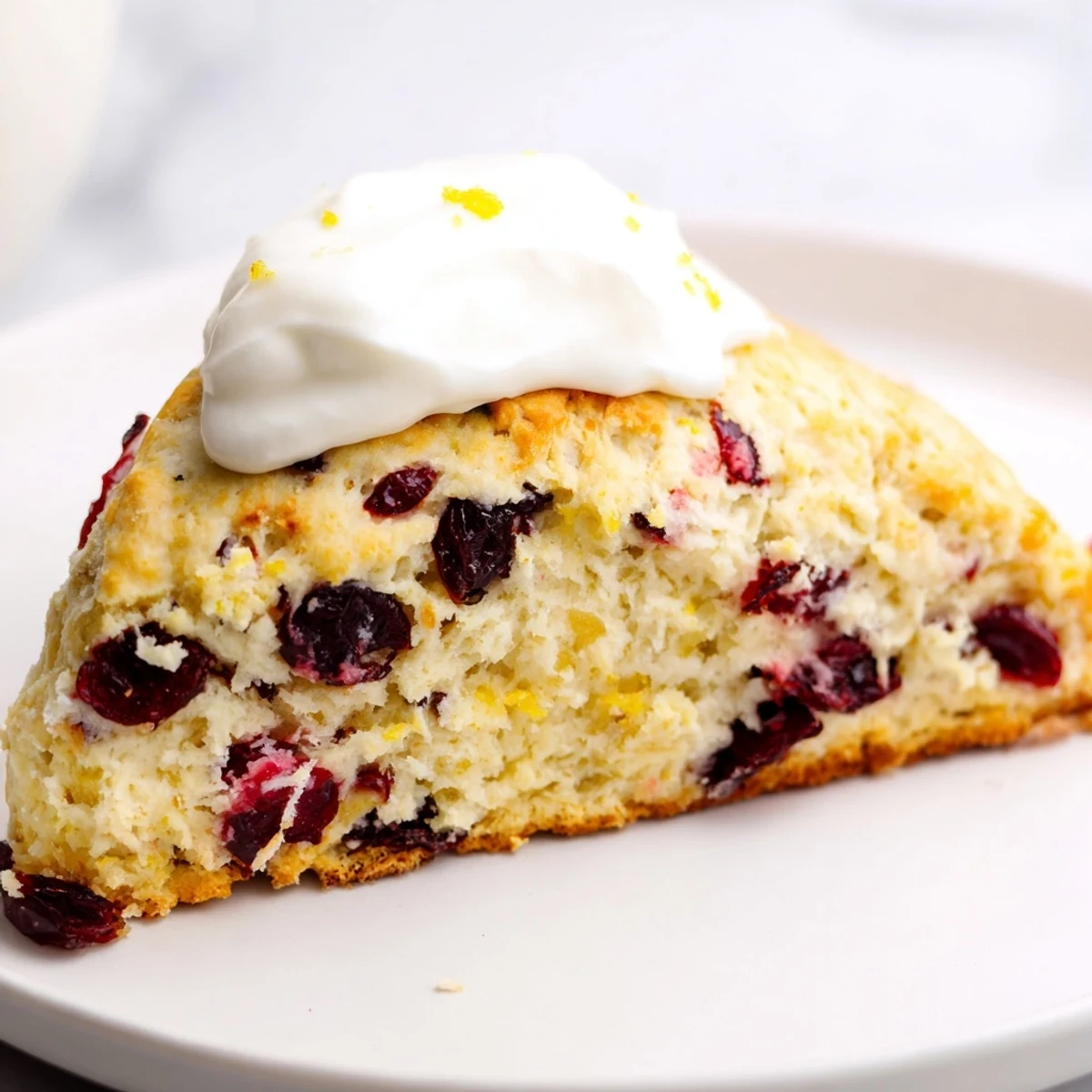 A close-up of freshly baked cranberry scones, showing juicy cranberries and a flaky texture.