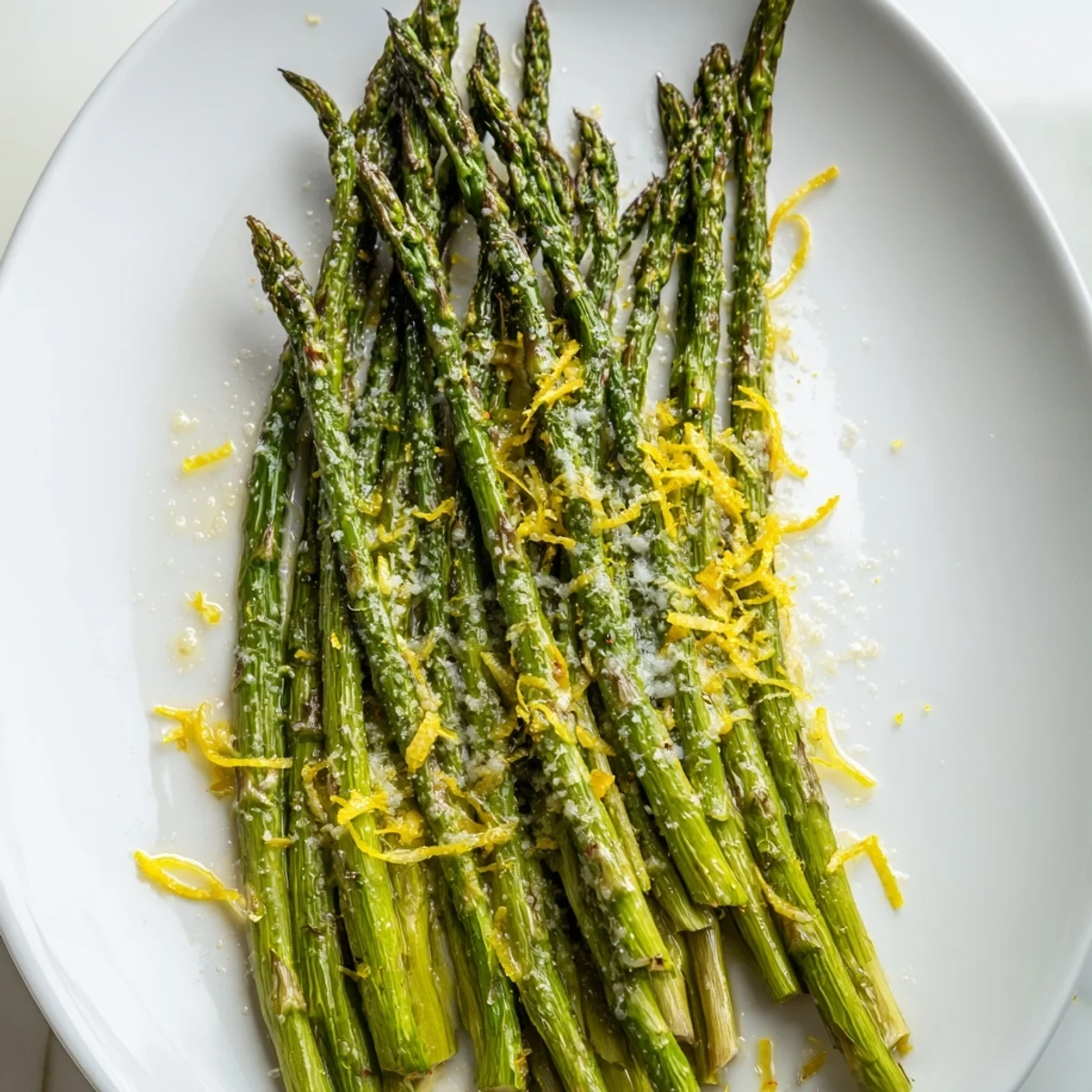 Golden-brown roasted asparagus, Parmesan-dusted with lemon zest, is presented on a baking sheet.