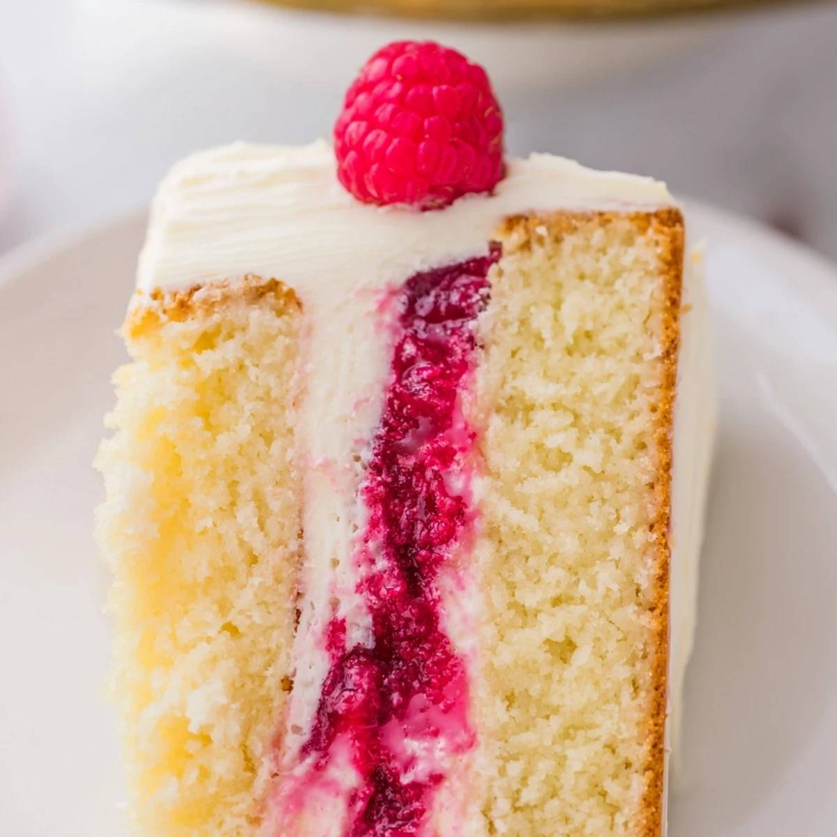 Feuchter, mehrschichtiger Zitronenraspberry-Kuchen mit Buttercreme, belegt mit frischen Früchten und Zitronenzesten.