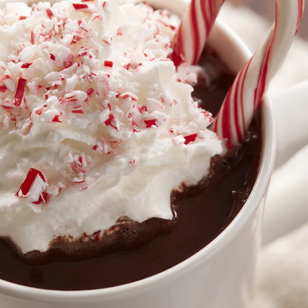 Peppermint Stick Hot Cocoa in einem weißen Becher, garniert mit geschlagener Sahne und zerknittertem Bonbon.