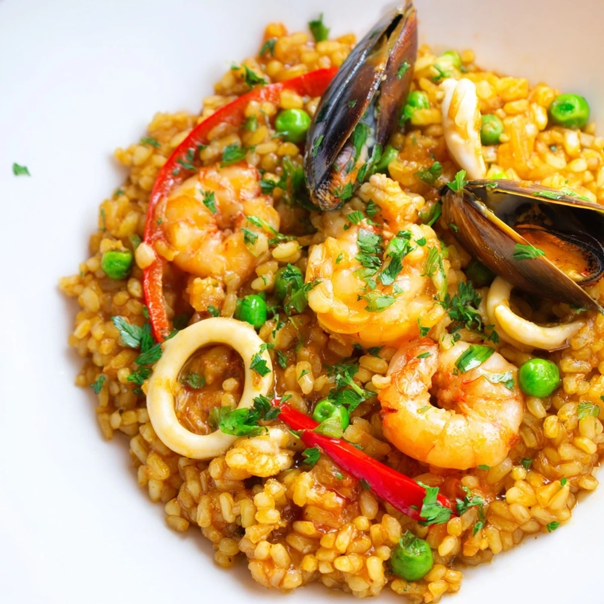 Romantic Seafood Paella with Saffron liegt goldgelb in der Pfanne, garniert mit Petersilie und frischen Zitronenscheiben, bereit zum Servieren.