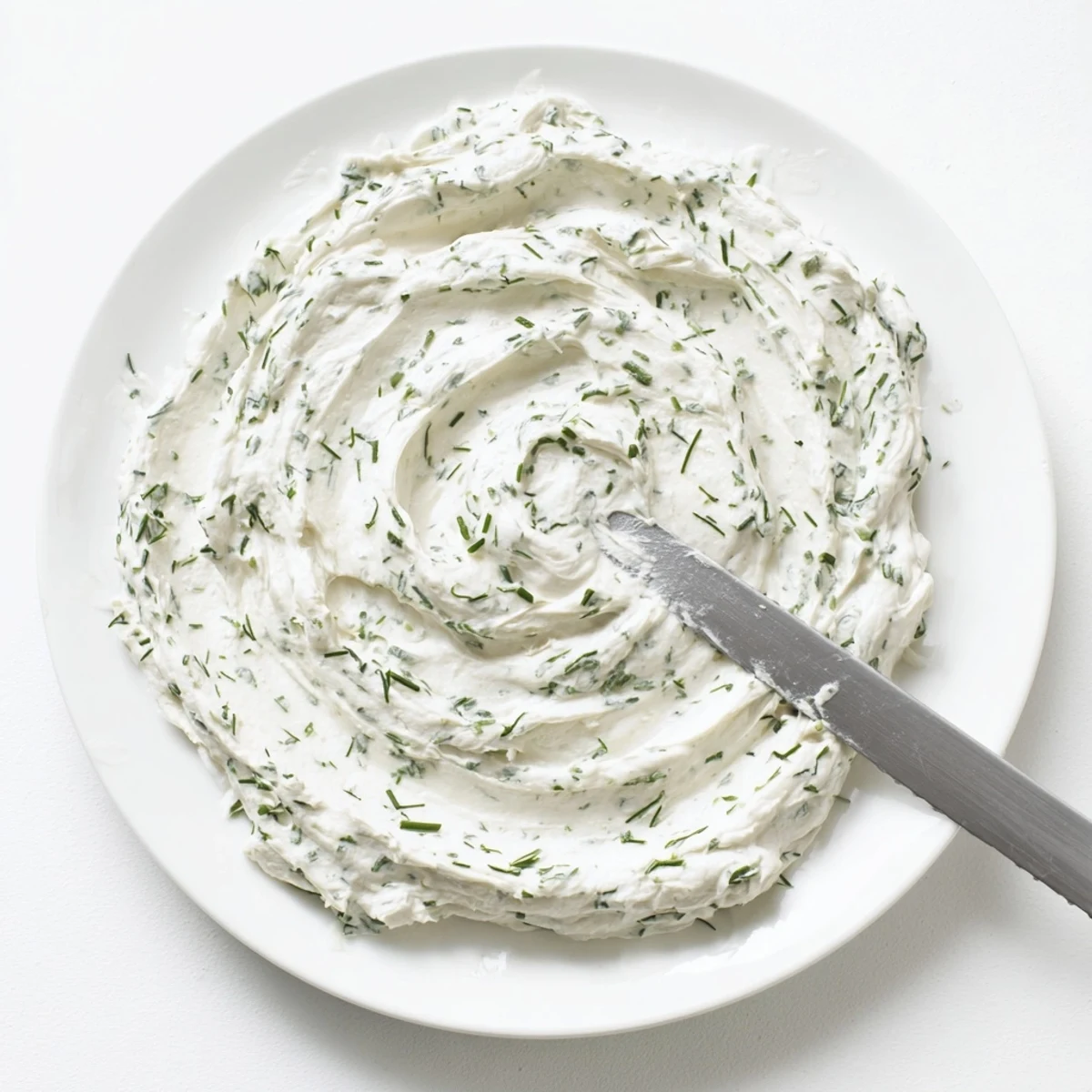 Eine Schüssel mit cremigem Creamy Appetizer Spread Dip, garniert mit frischen Schnittlauch- und Petersilienstücken, serviert mit knusprigen Crackern und bunten Gemüsestiften.