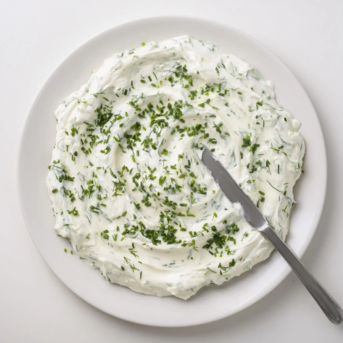Ein Glas mit frisch zubereitetem Creamy Appetizer Spread Dip, umhüllt von duftenden frischen Kräutern und einer Zitronenscheibe auf einem rustikalen Holztisch.
