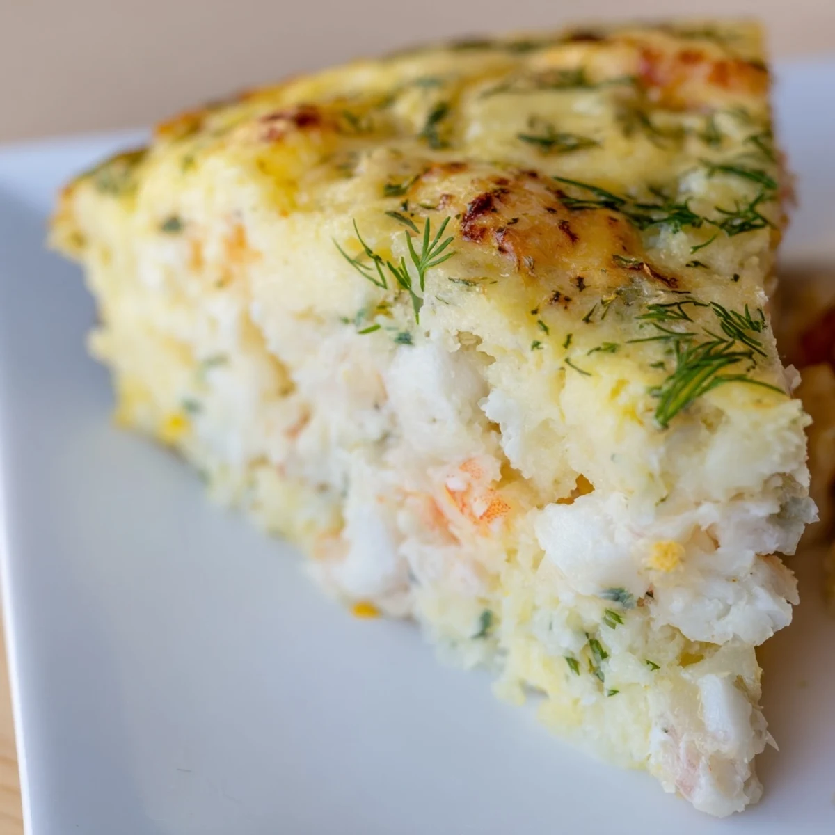 Detailaufnahme des feuchten Fisch-Apetitkuchens mit sichtbarem Schinkeneinlage und frischen Kräutern in einem hellen Ambiente.