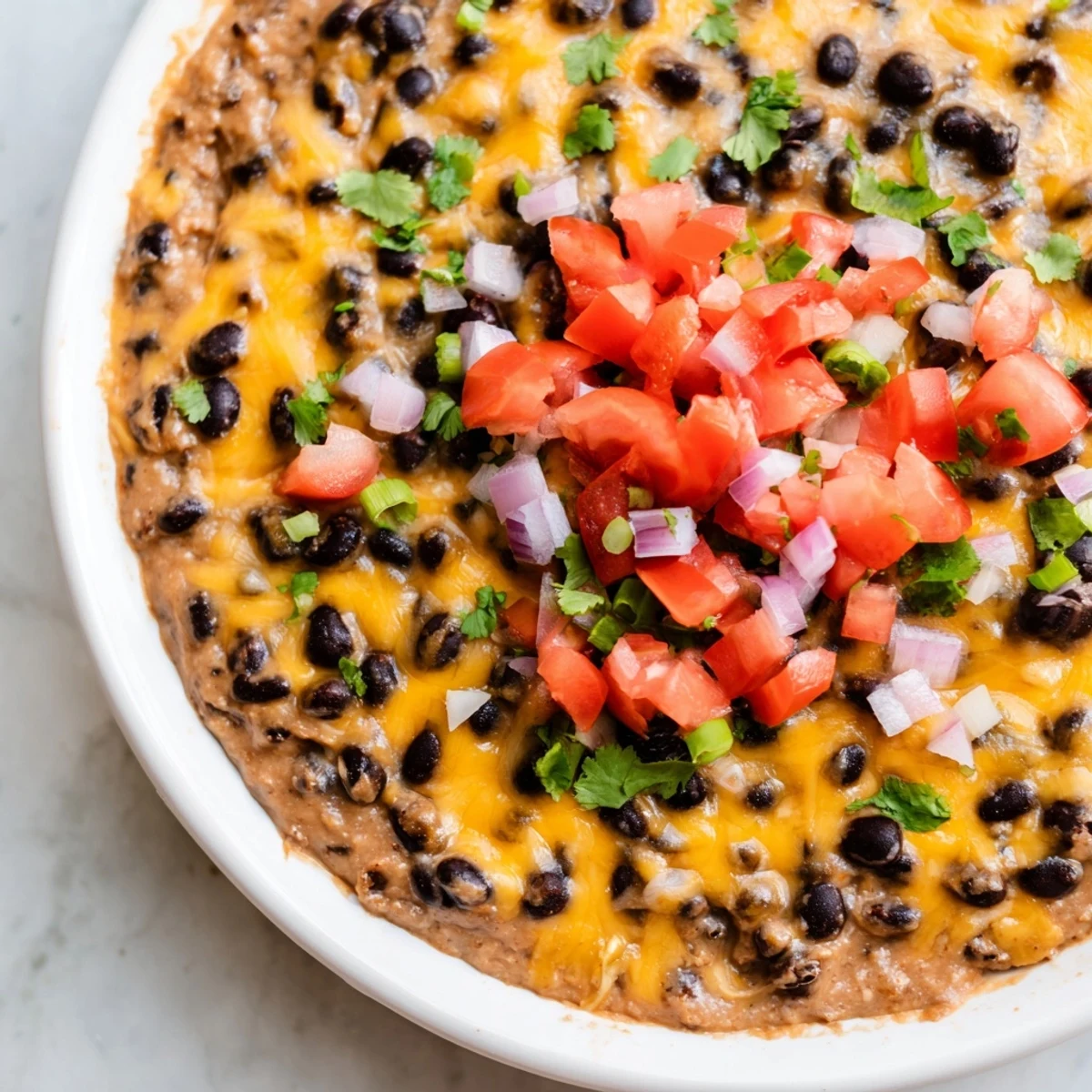 Geschmolzener Cheddar bedeckt eine cremige Bean Dip Schicht, frisch aus dem Ofen und perfekt für Partys serviert.