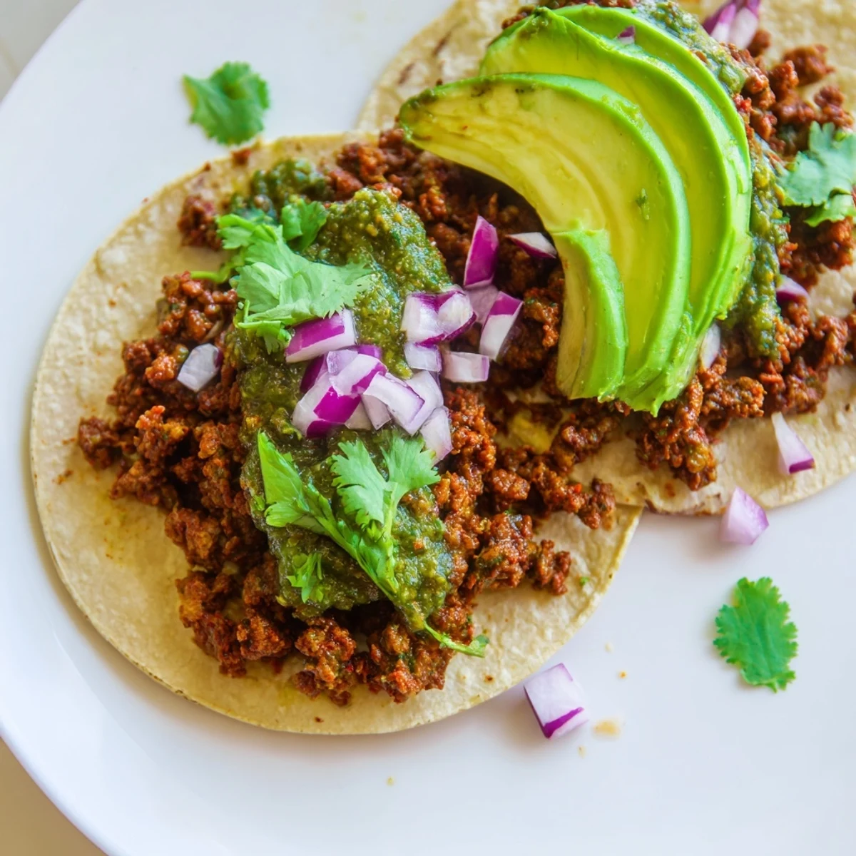 Zubereitete Spicy Beef Tacos mit saftigem Rindfleisch, grüner Salsa und zerkrümeltem Käse auf einem rustikalen Holztisch.
