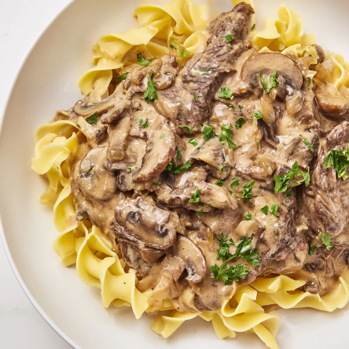 Das Beef Stroganoff mit Mushroom Gravy duftet nach gebratenen Pilzen und zarter Rindfleischstreifen, frisch mit Petersilie garniert auf dem Teller.