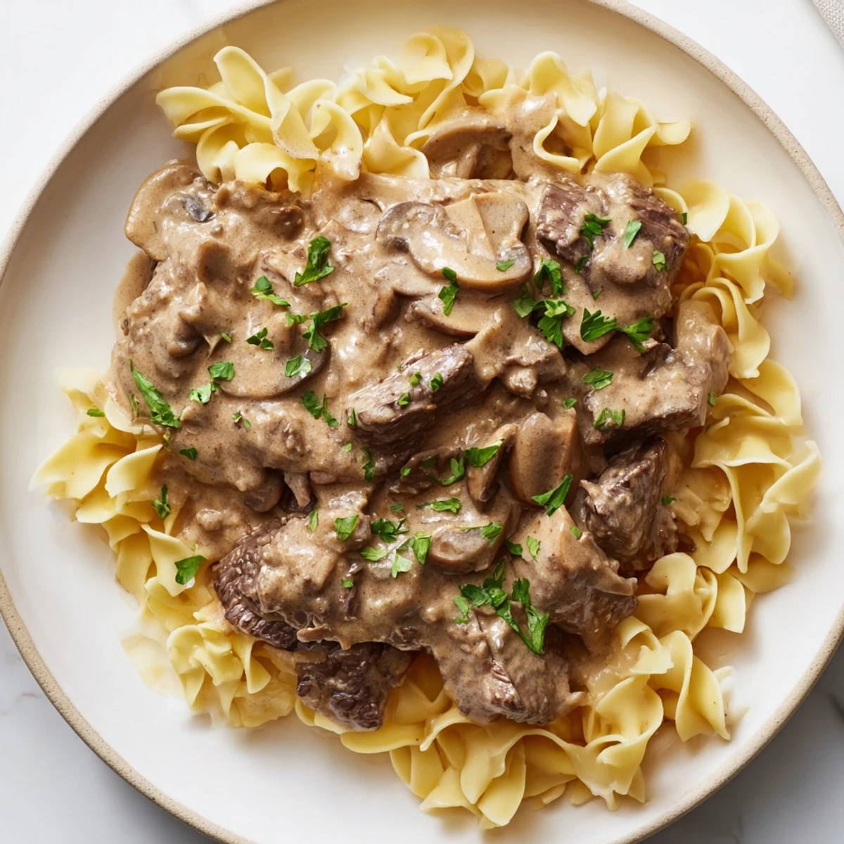 Hausgemachte Beef Stroganoff mit Mushroom Gravy: goldbraune Rinderstreifen in samtiger Sauce über weichen Eiernudeln für ein wohliges Comfort-Food-Erlebnis.