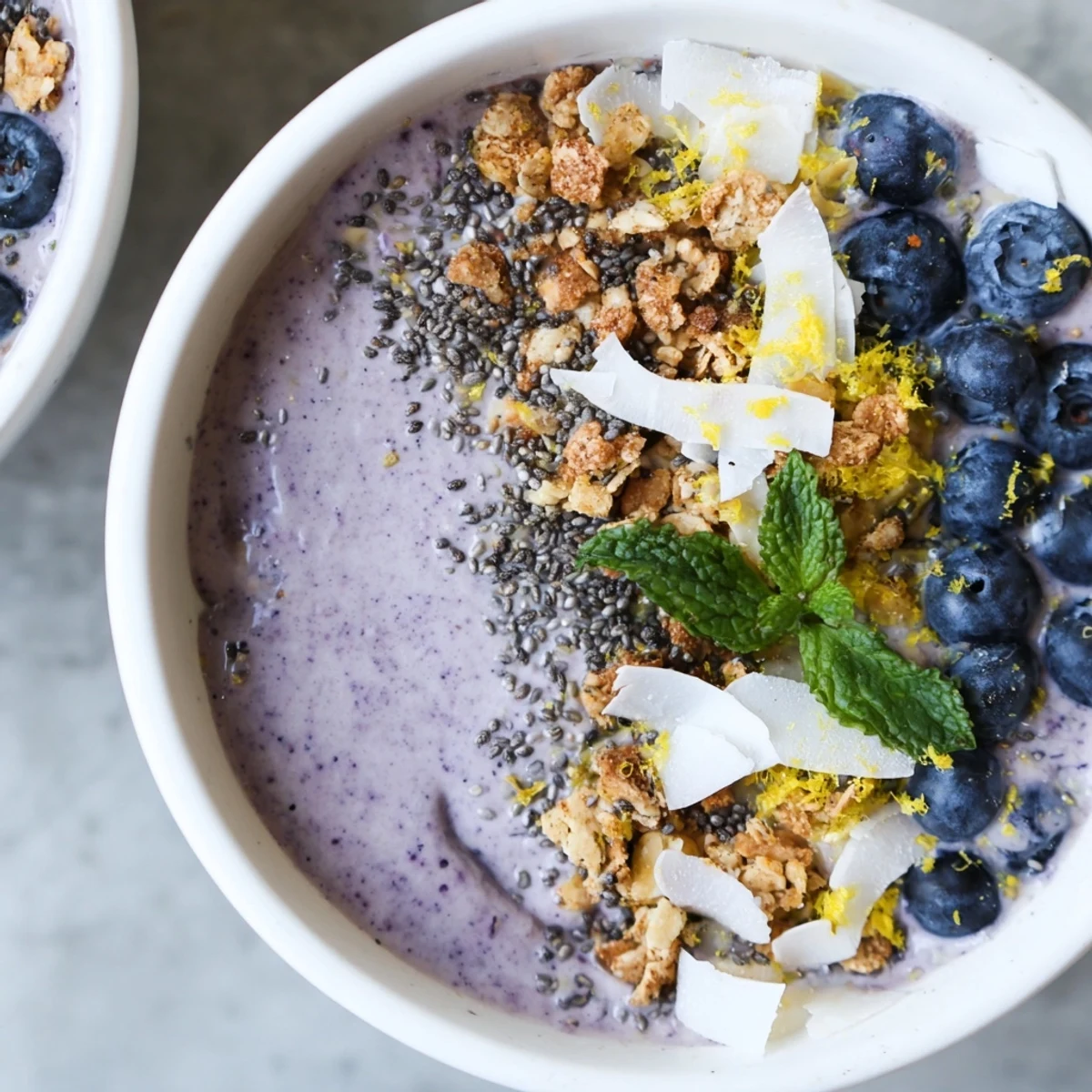 Gelbblauer Lemon Blueberry Smoothie Bowl mit frischen Früchten und knusprigem Granola im Frühstücksschüsseltopf.