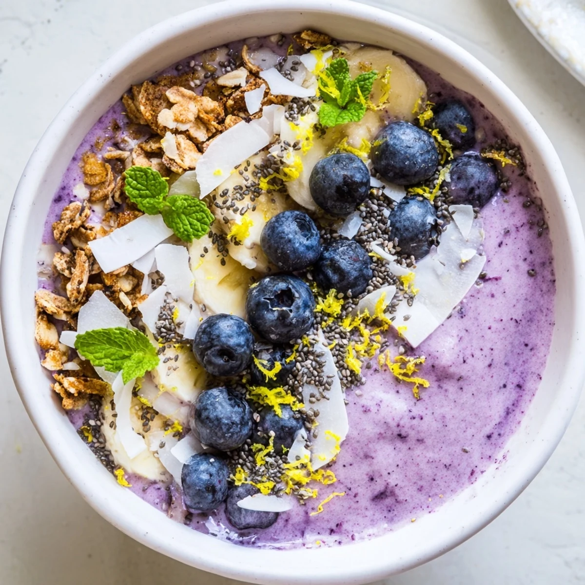 Ein leckeres, farbenfrohes Lemon Blueberry Smoothie Bowl mit Blaubeeren, Zitrusnote und knackigem Topping.