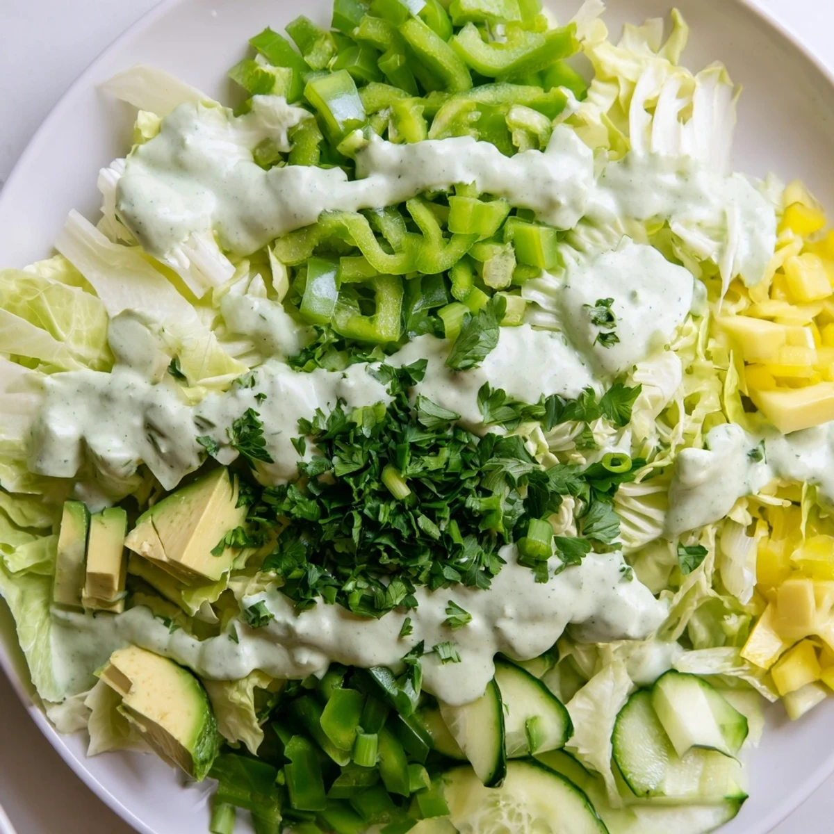Frischer Green Goddess Salad mit Avocado, cremigem Dressing und knackigem Gemüse auf rustikalem Holztisch
