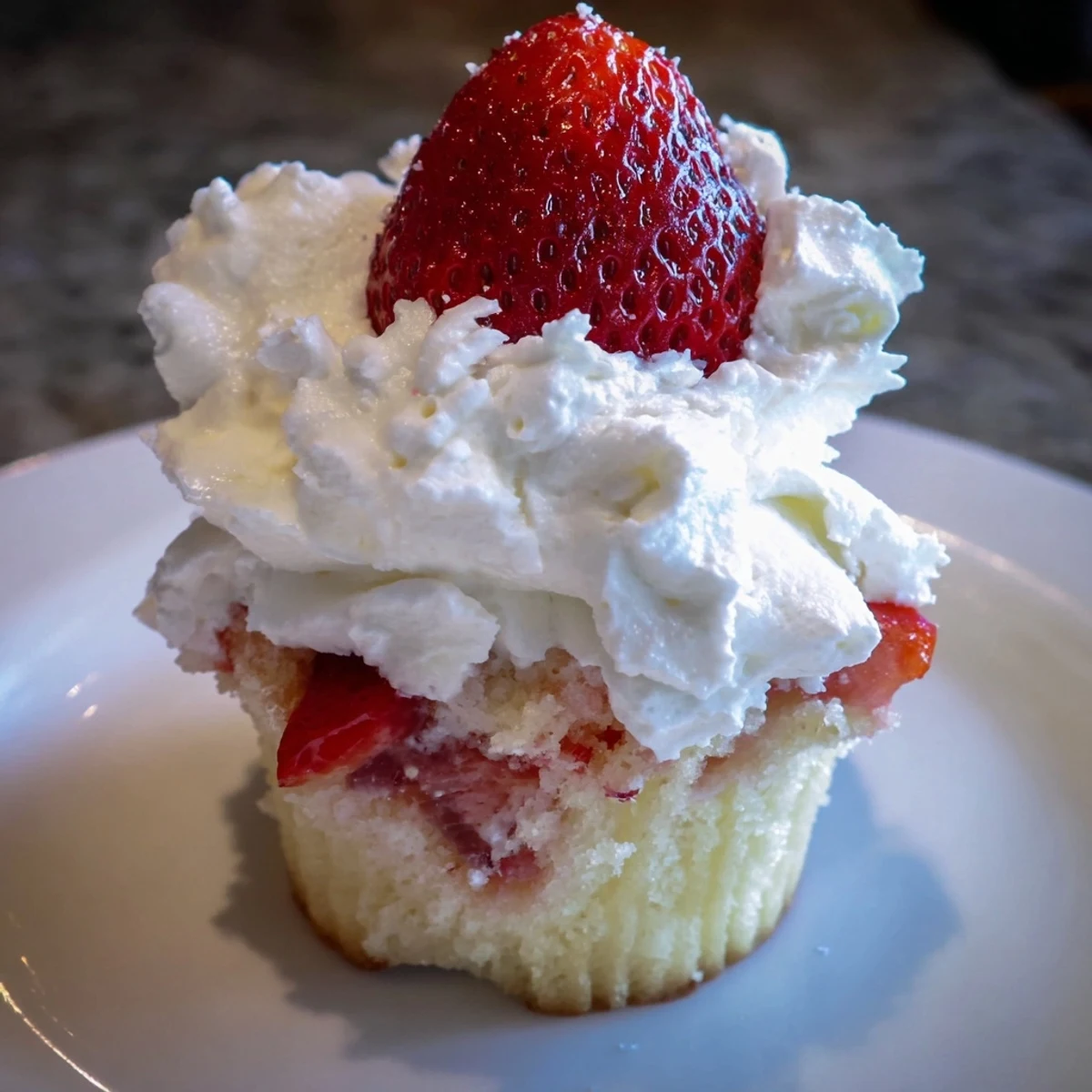 Fluffy vanilla Strawberry Shortcake Cupcakes filled with sweet strawberries and topped with whipped cream.