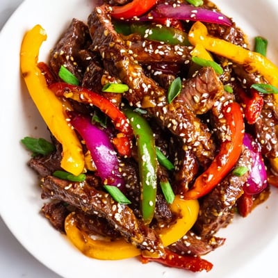 Ein Teller voller Spicy Beef and Pepper Stir Fry mit glasiger, scharfer Sauce, knusprigen Paprikastreifen und zartem Rindfleisch, perfekt für ein schnelles Abendessen.