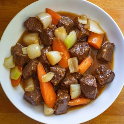 A ladle pours rich, savory broth over tender beef chunks, potatoes, carrots, and parsnips in this comforting meal.