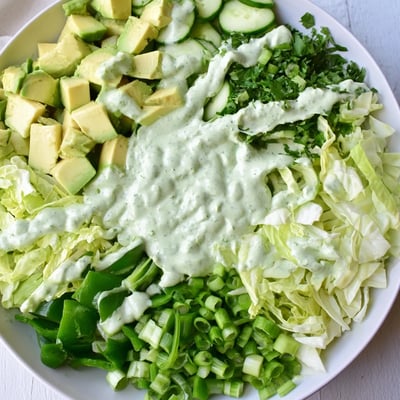 Green Goddess Salad mit Avocado in einer Glas-Schüssel mit frischen Kräutern und knusprigem Grünzeug
